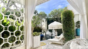 A serene indoor garden with a hexagonal white partition, a seating area with white wicker furniture, and a small water feature. - Moon Villas Umalas (Kerobokan)