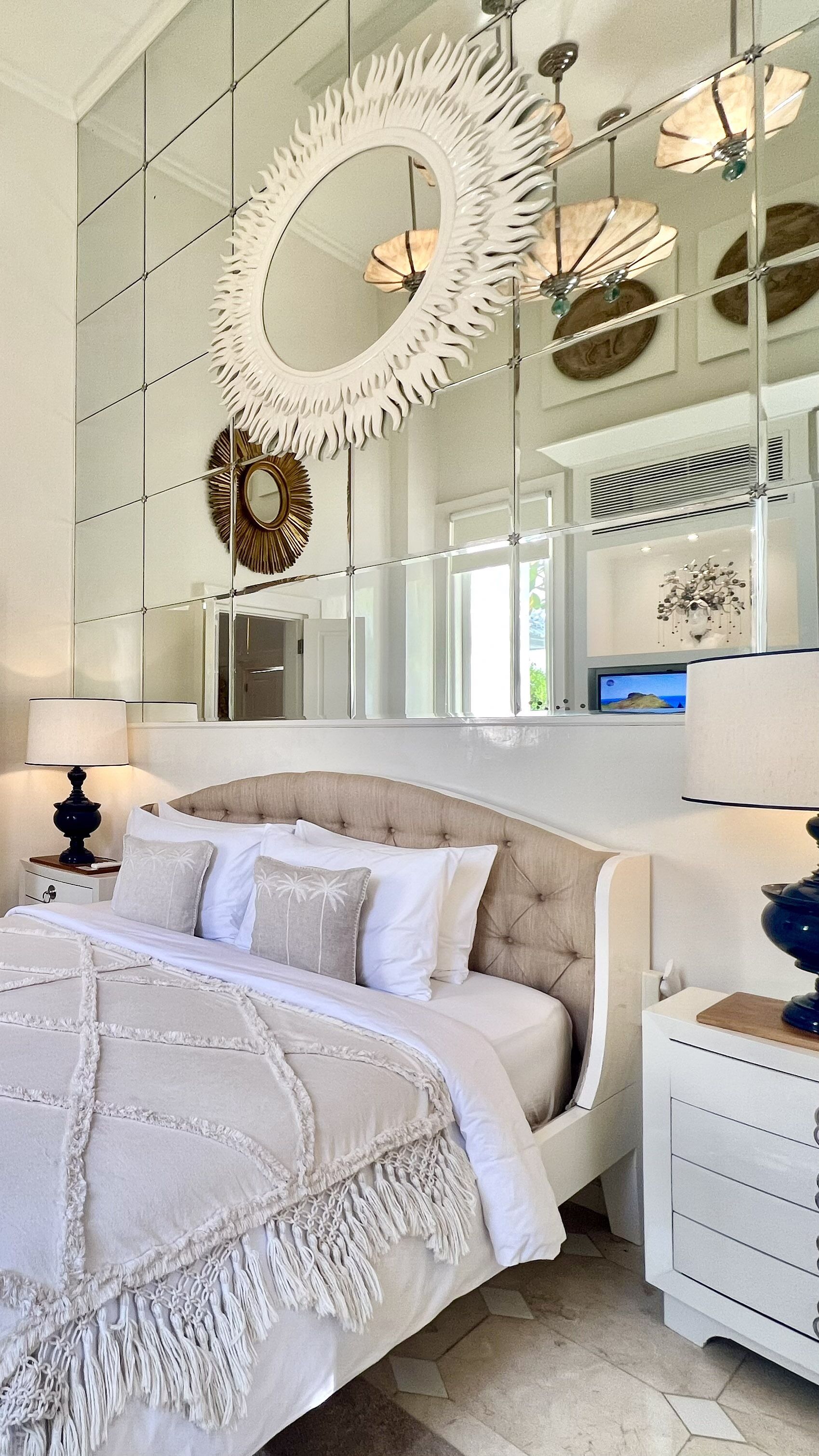 A bedroom with a large bed, a nightstand, a dresser, and a mirror.