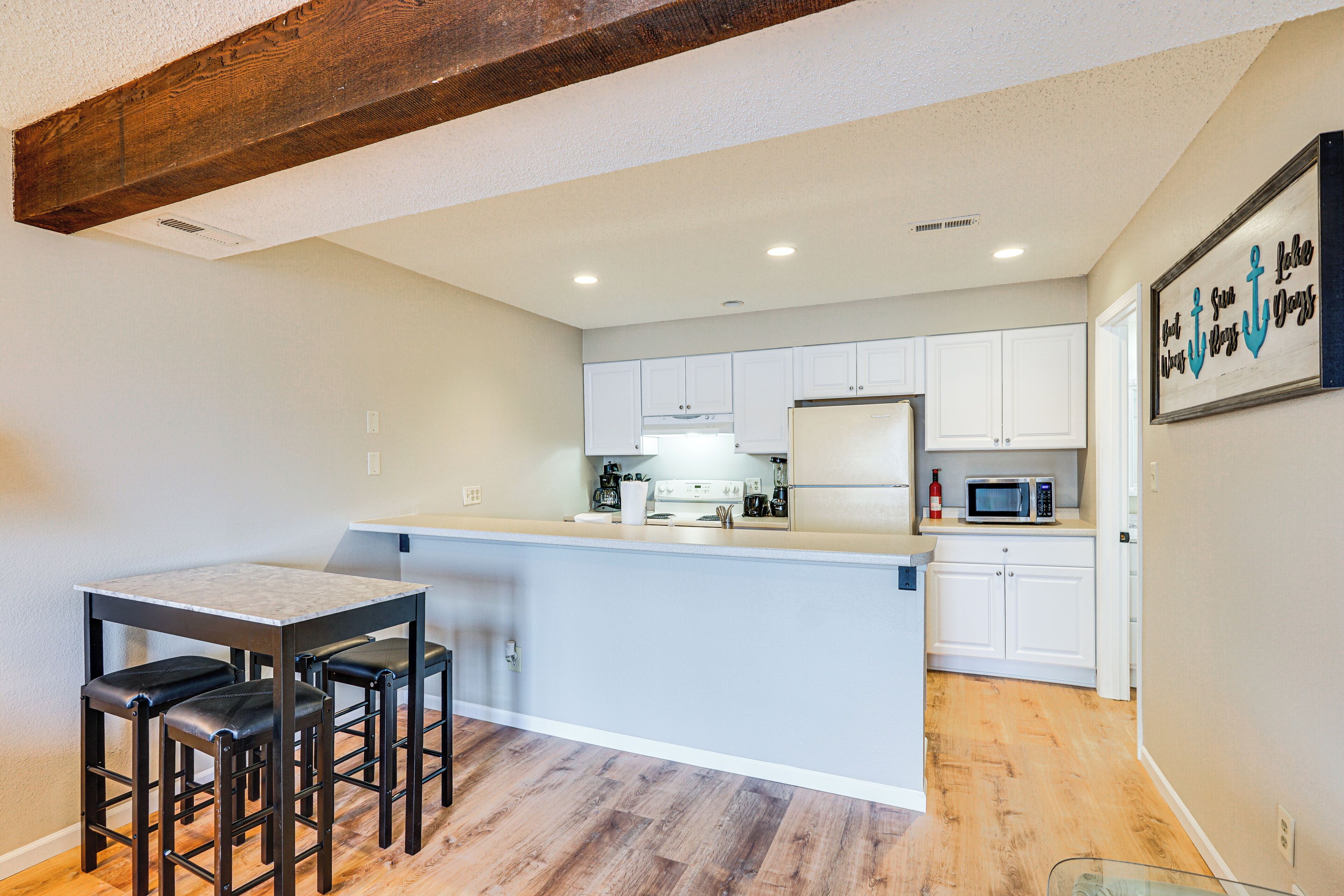 A modern kitchen with white cabinets, a wooden island, and a bar area with stools.