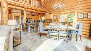 A spacious log cabin interior with a dining area, kitchen, and a balcony. - Mountain Cabin w/ Hot Tub: 4 Mi to Shaver Lake! (Shaver Lake)
