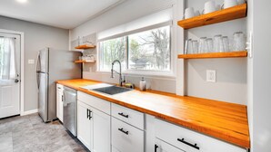 A kitchen with white cabinets, a stainless steel refrigerator, a wooden countertop, and a window with a view of trees. - Updated Home: Central Oak Ridge Location (Oak Ridge)