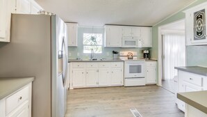 A kitchen with white cabinets, a stainless steel refrigerator, a microwave, and a sink. - Lakefront Prosperity Home w/ Private Boat Dock (Prosperity)