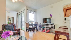Een woonkamer met een bank, eettafel, stoelen, een televisie en een raam met gordijnen.