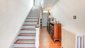 A staircase with wooden steps and white railings, leading to a landing with a radiator and a wooden dresser. - Experience a 17th-century Spring Manor (Norristown)