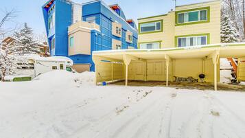 A snow-covered outdoor area with a covered seating area and a building with multiple windows and balconies.