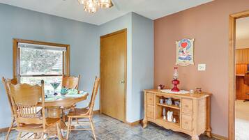 A dining area with a wooden table and chairs, a wooden cabinet, and a window with blinds.