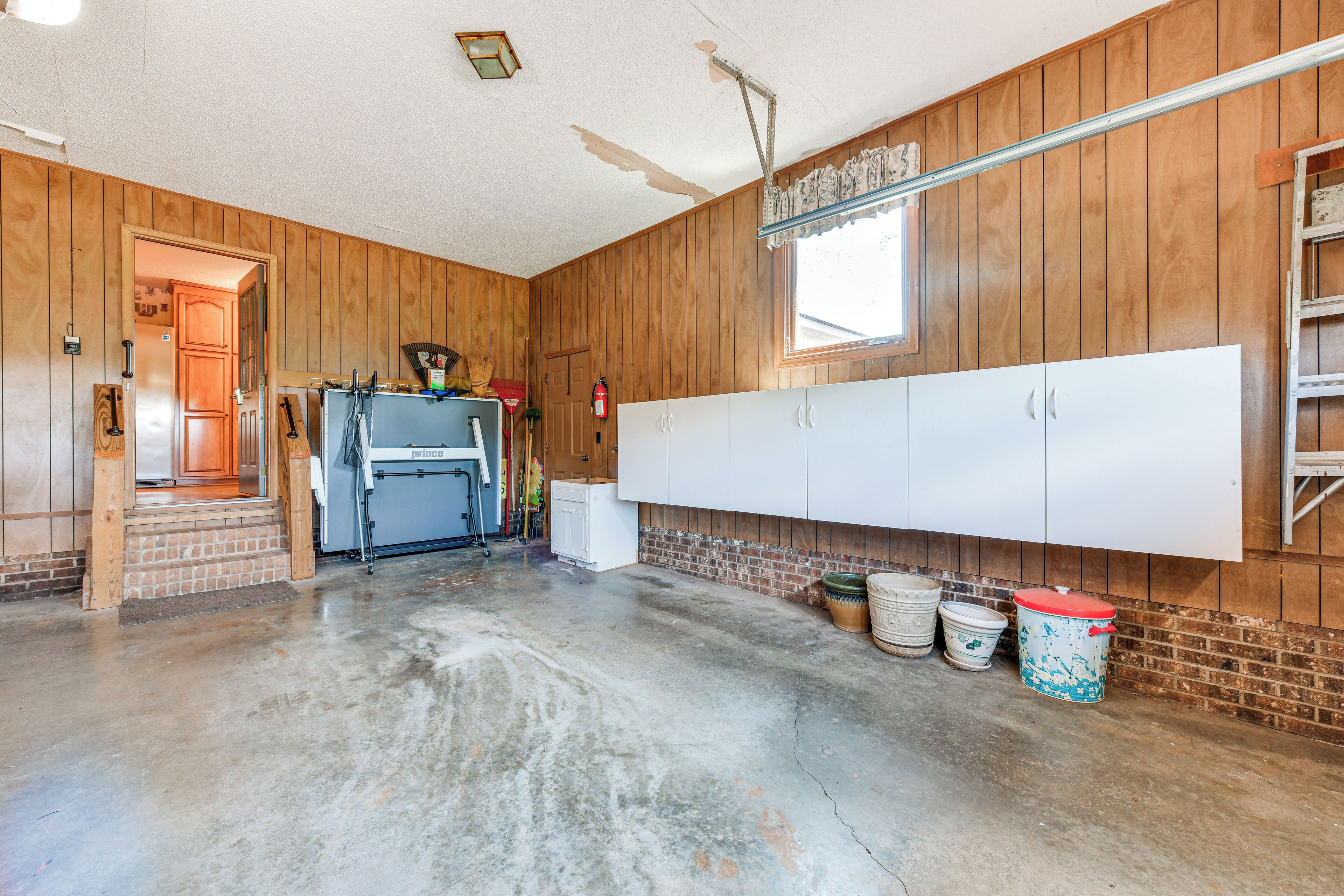 A spacious room with wooden walls, a large white cabinet, and a concrete floor.