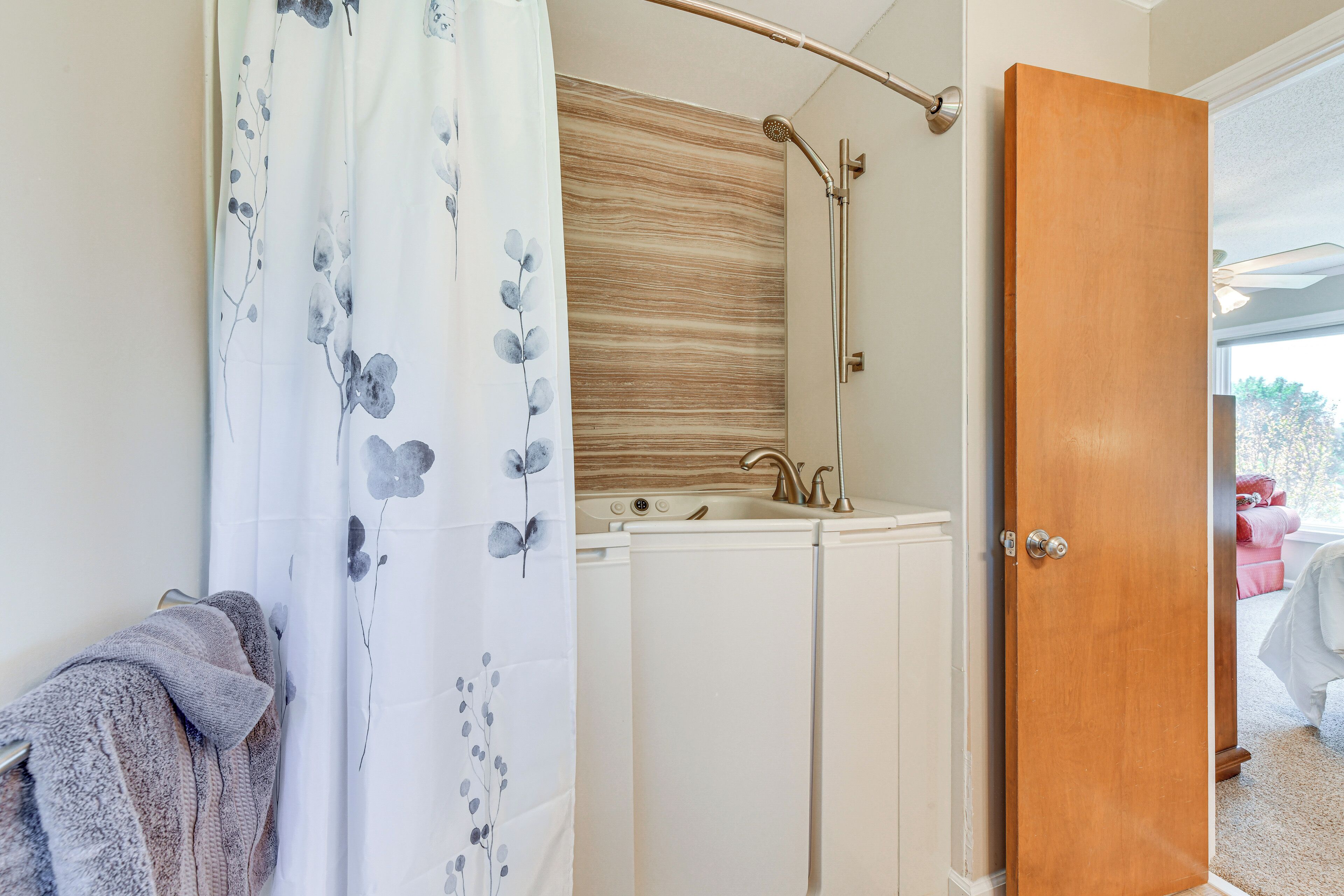 Une salle de bain avec une douche, un lavabo et une porte en bois.