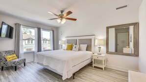 A bedroom with a bed, bedside tables, a ceiling fan, a TV, and large windows. - Santa Rosa Beach Townhome ~ 4 Mi to Beach! (Santa Rosa Beach)