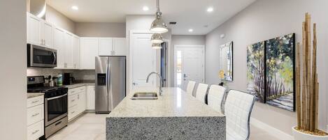A modern kitchen with white cabinets, stainless steel appliances, and a granite countertop.