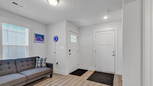 Un salon moderne avec un canapé gris, une horloge et une porte.