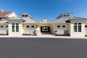 A modern building with a central entrance, stone accents, and a clear blue sky. - 4 BR 4 BA Hidden Gem Min Disney 1804ft (Kissimmee)
