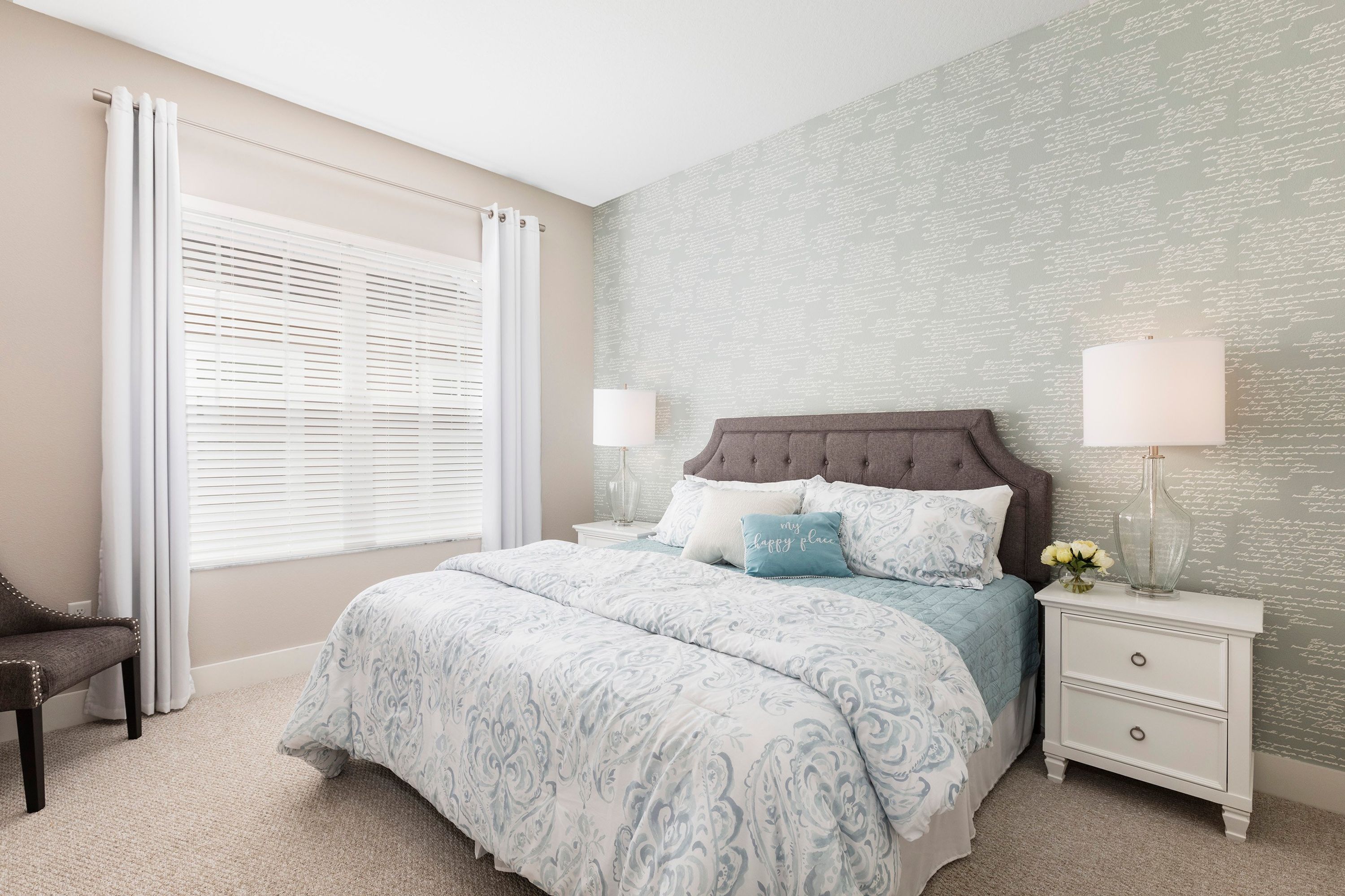 A bedroom with a bed, nightstands, a chair, and a window with blinds.