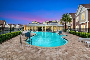A swimming pool with lounge chairs and a covered area, surrounded by houses with a uniform architectural style. - 5 BR 6 BA Villa 5min Disneyworld Hot Tub BBQ (Kissimmee)