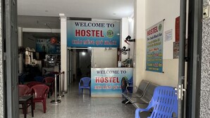 A hostel entrance with a welcome mat, plastic chairs, and tables. - Hostel 15A (Da Nang)