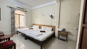 A clean, well-lit hotel room with a large bed, a small table with a water bottle, and a bench. - Hostel 15A (Da Nang)