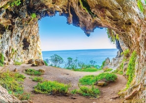 A natural cave opening with a dirt path leading to the sea, surrounded by greenery. - La Casa di Pietro - Fronte Mare nel Salento (Gagliano del Capo)