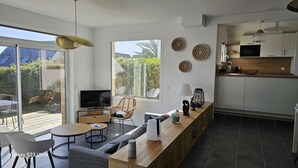 A modern living space with a TV, sofa, dining area, and kitchen. - Superbe Maison Entièrement Rénovée 2024, Lumineuse à 400 m de la Plage (Sarzeau)