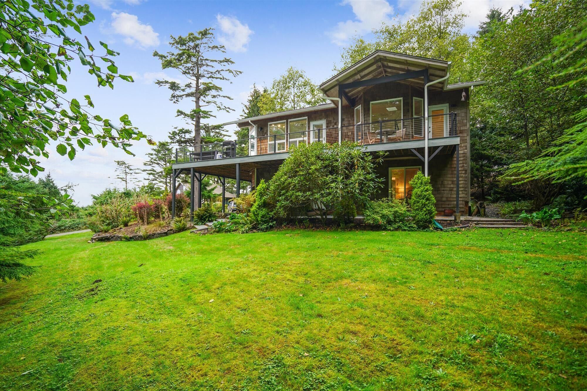 A two-story wooden house with a covered porch and a well-maintained garden.
