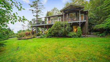 A two-story wooden house with a covered porch and a well-maintained garden.