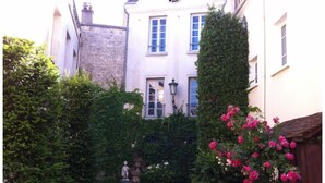 A narrow alleyway with a gravel path leading to a building with a statue and a lamppost. - Croissy Sur Seine Superbe 2pièces 60m2 15min Paris (Croissy)