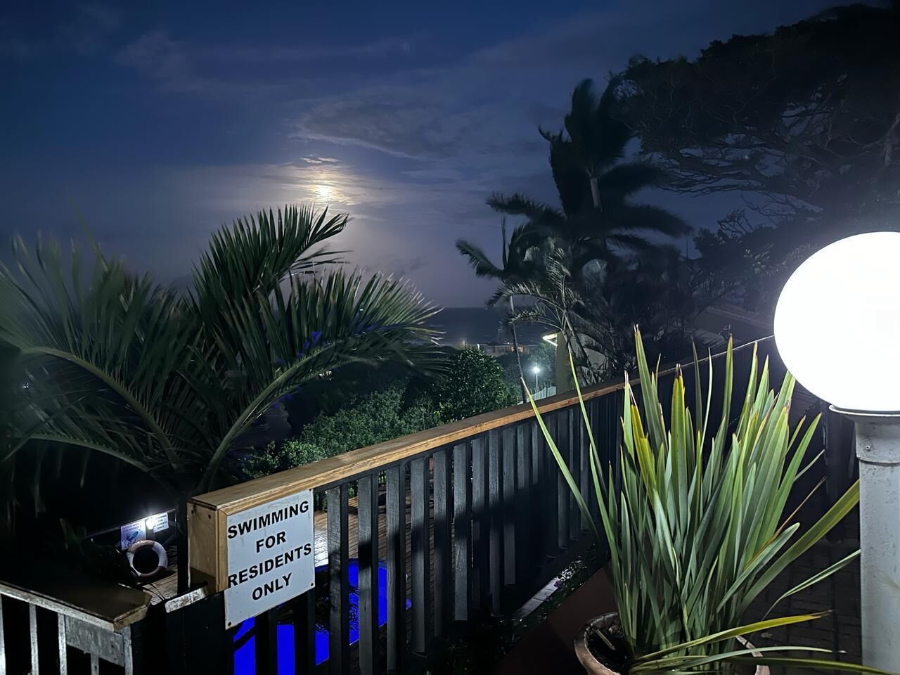 A nighttime view of a pool area with a sign indicating it is for residents only.