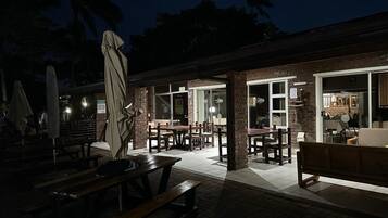An outdoor patio area with brick flooring, wooden tables, and benches.
