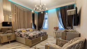 A modern bedroom with a large bed, a TV mounted on the wall, and a marble floor. - Luxury Suites (Cluj-Napoca)