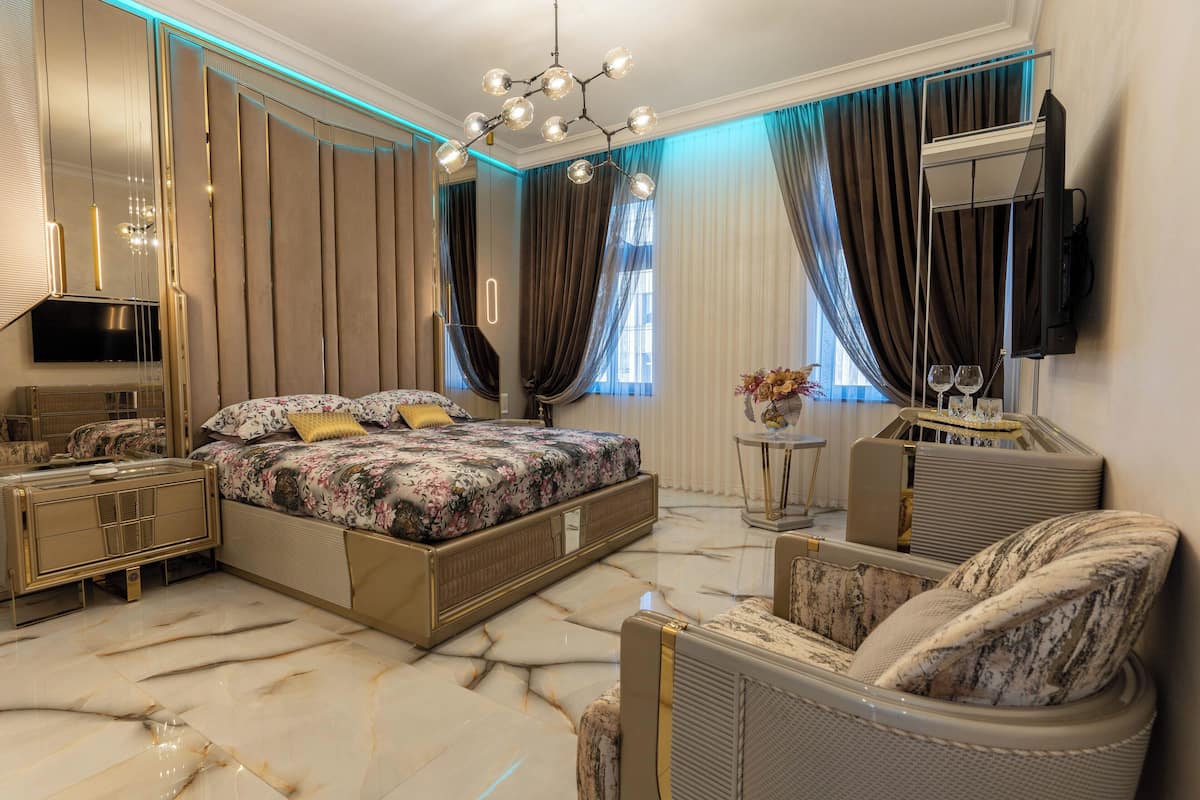 A modern bedroom with a large bed, a TV mounted on the wall, and a marble floor.