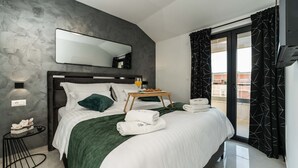 A modern hotel room with a large bed, a bedside table with a glass of orange juice, a tray of croissants, and neatly folded towels. - Villa Antea Dalmacija (Privlaka)