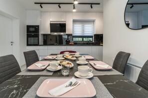 A modern dining area with a marble table, pink placemats, and a glass of water. - Villa Antea Dalmacija (Privlaka)