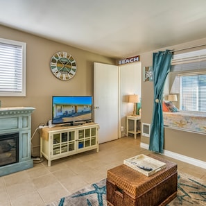 A living room with a television, a fireplace, a clock, and a sign that says "Welcome to the Beach."