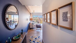 A hallway with a mirror, framed artwork, a console table, and a view to a living area with a sofa and chairs. - Casa Costera | Walk to Romantic Zone & Beach (Puerto Vallarta)