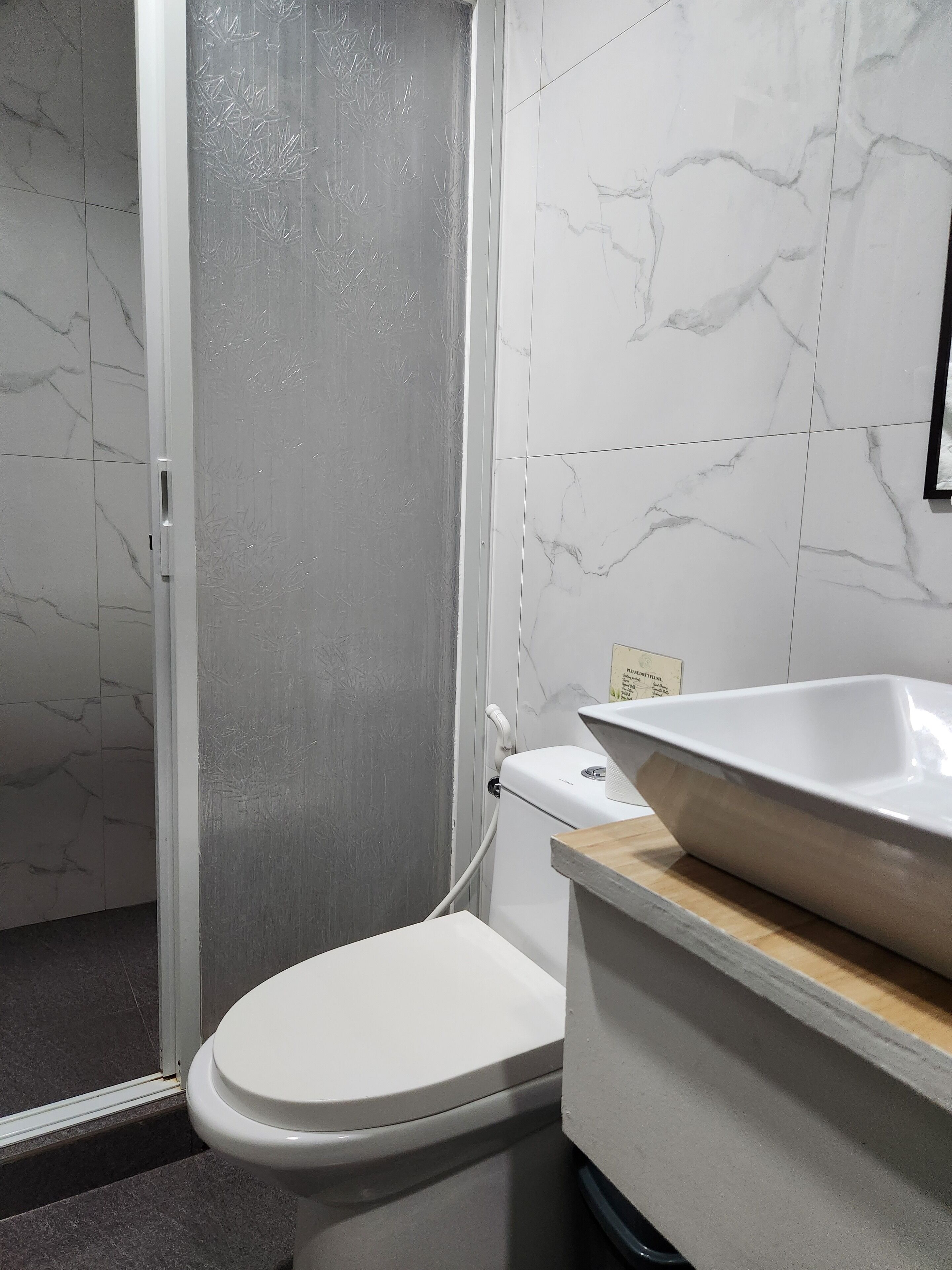A bathroom with a toilet, a shower, and a sink.