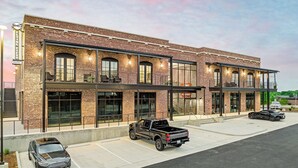A modern hotel with a brick facade, large windows, and a covered outdoor seating area.