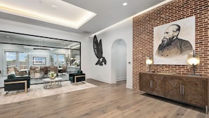 A modern interior with a brick accent wall, a large portrait, and a glass partition.