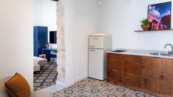 Una cocina compacta con refrigerador, armarios de madera y un lavamanos.