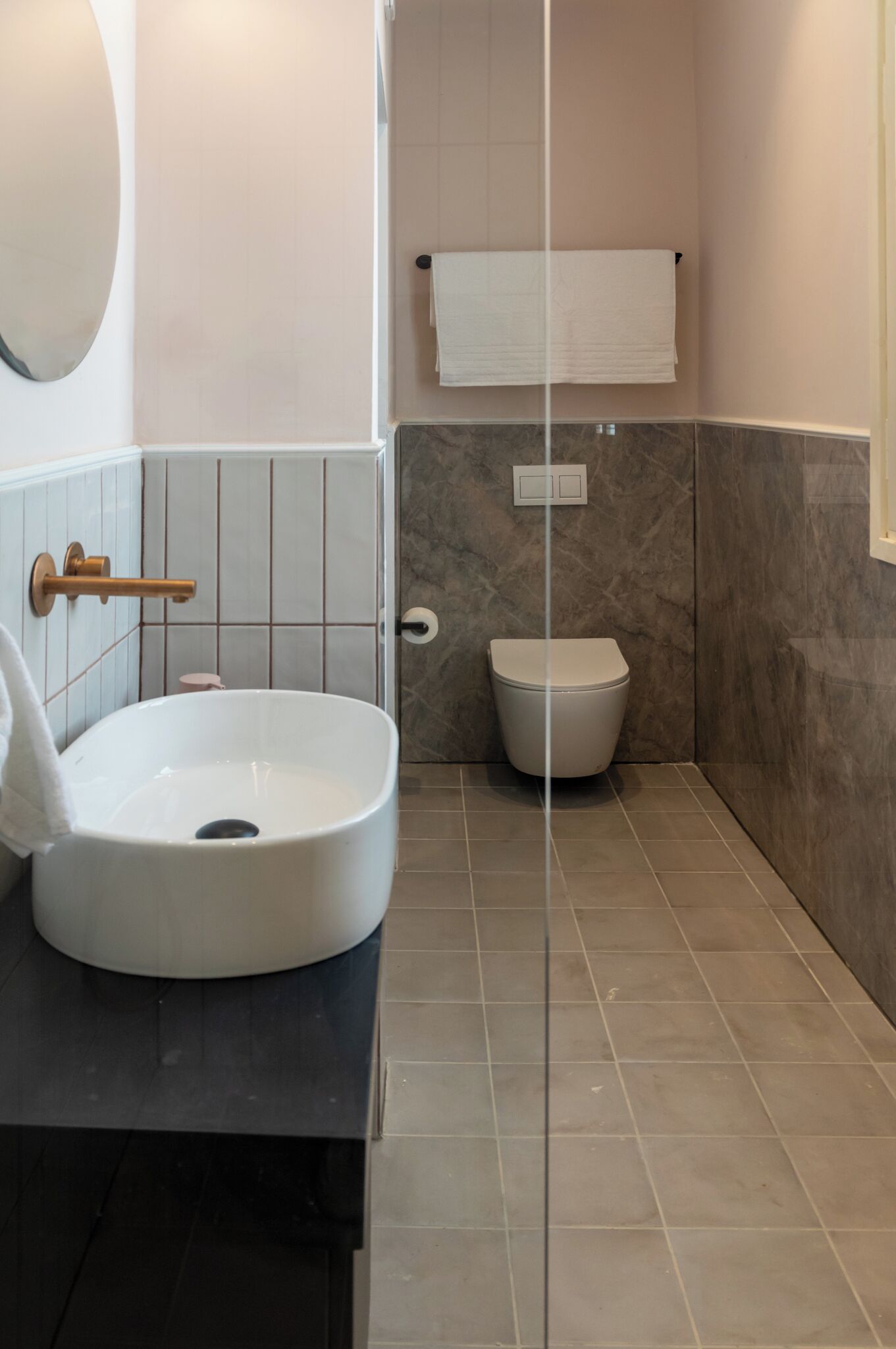 Un baño con un lavamanos blanco, un inodoro y un perchero para toallas.