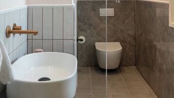 Un baño con un lavamanos blanco, un inodoro y un perchero para toallas.