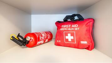 A red first aid kit and a fire extinguisher in a storage compartment.