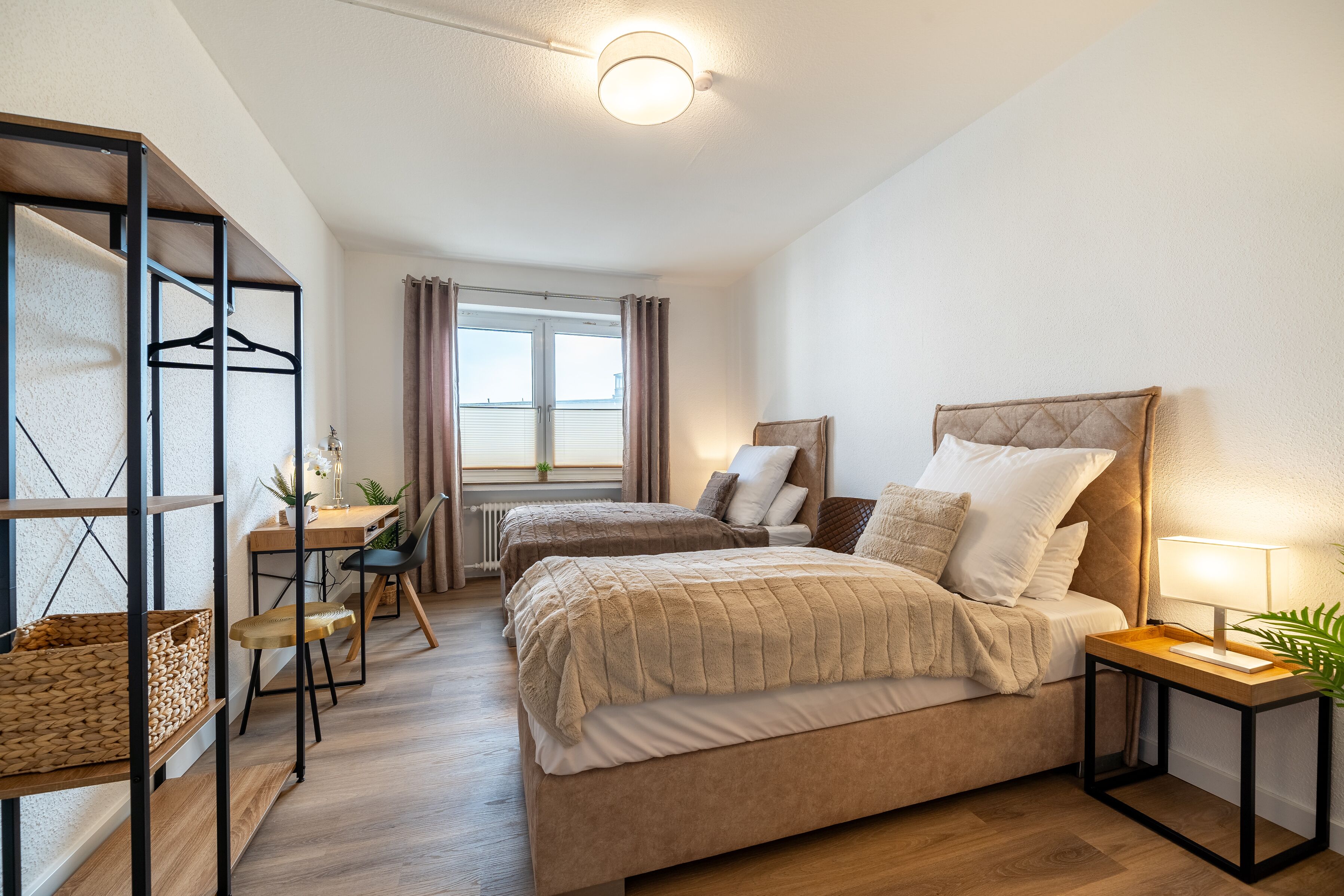 A bedroom with two beds, a desk, and a chair.