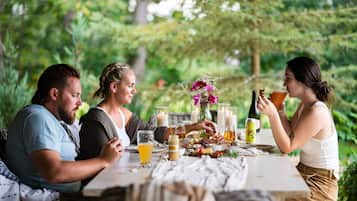 Un grupo de personas cenando al aire libre en una mesa con diversos platos y bebidas.