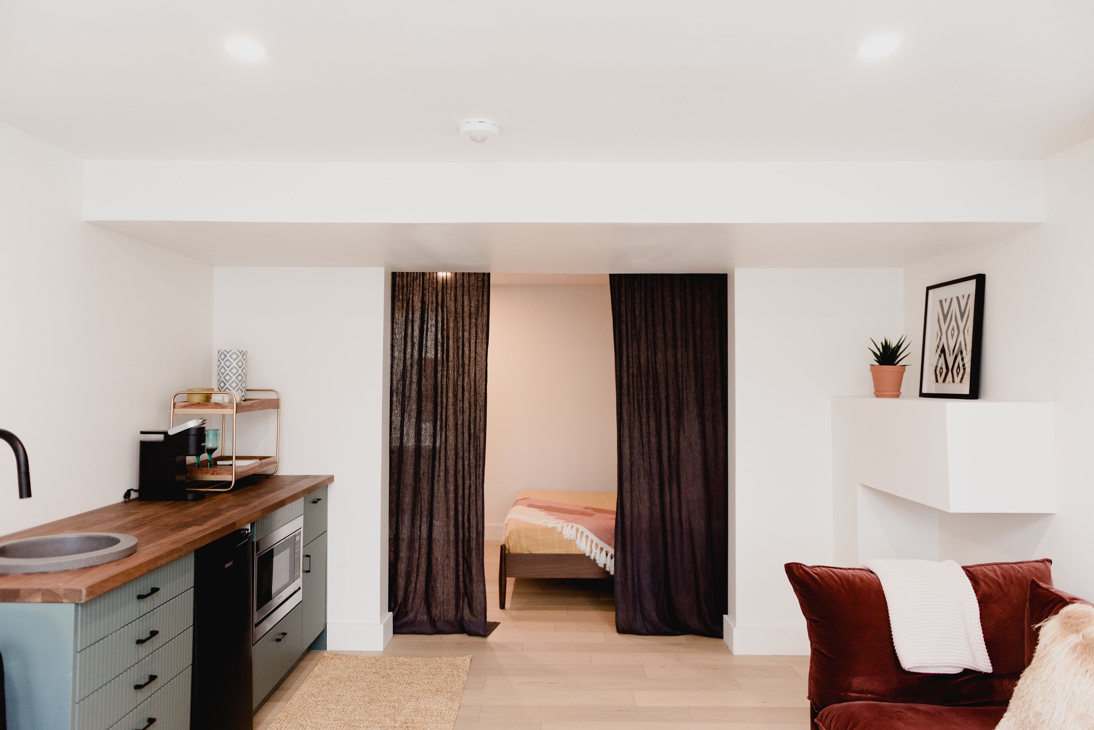 Un espacio habitable compacto con kitchenette, cama y zona de estar.