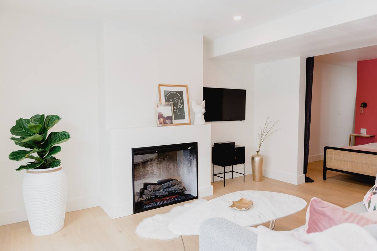 Una sala de estar moderna con chimenea, un jarrón blanco grande y un televisor de pantalla plana montado en la pared.
