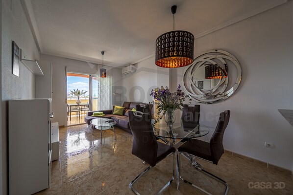 Enjoy meals at the glass-top table in this stylish living space, featuring a unique circular mirror and comfortable seating for four.