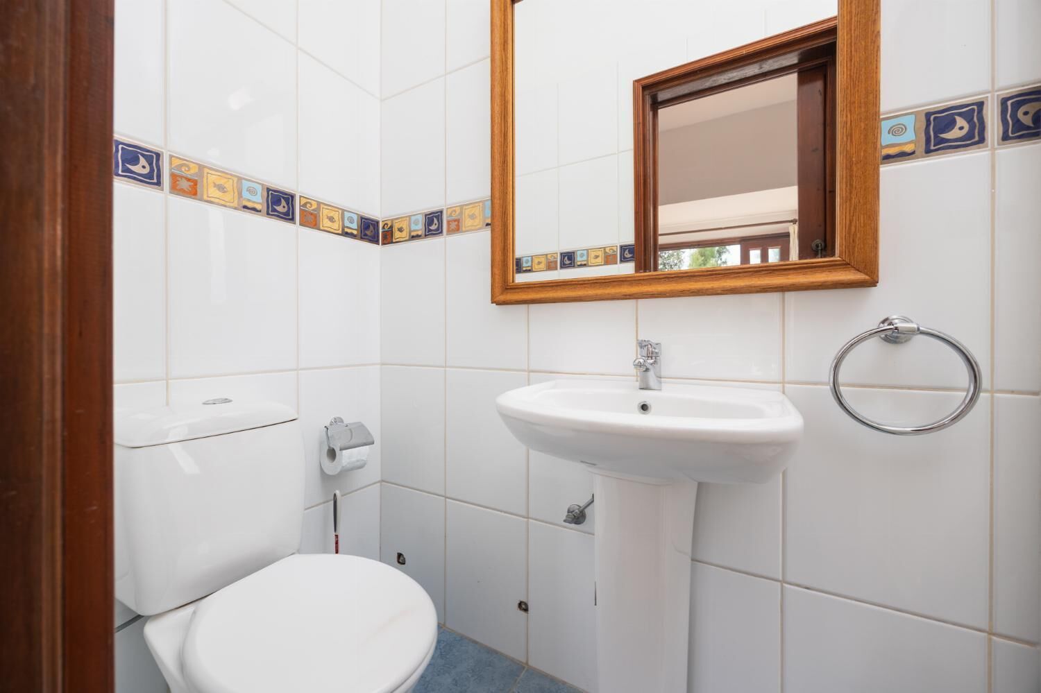 Een kleine badkamer met toilet, wastafel en spiegel.
