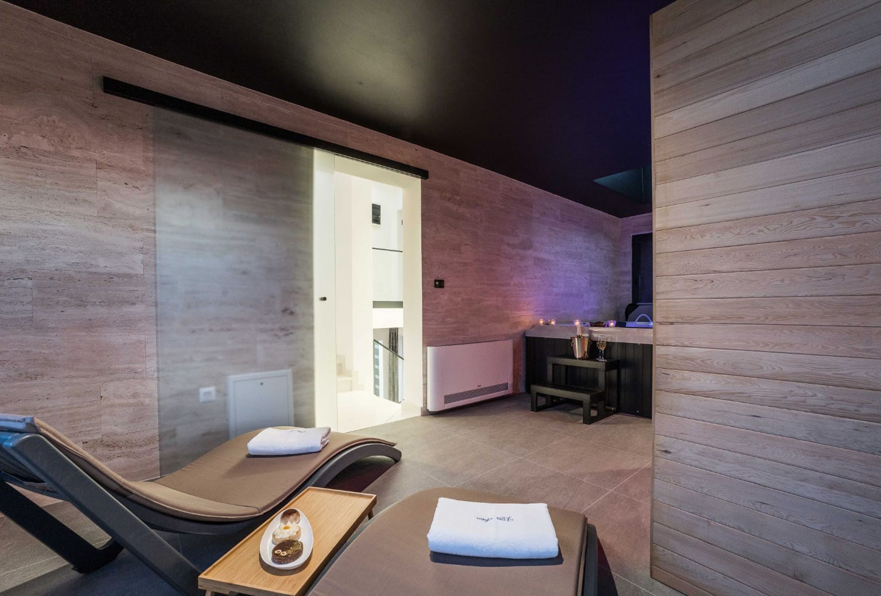 Un moderno spa con mesas de masaje, un mostrador de recepción y una puerta de salida visible.
