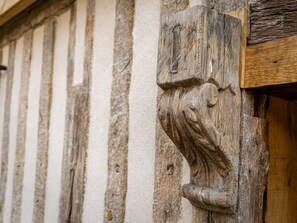 A close-up of a wooden carving on a building's exterior, featuring a lion's head and a claw. - Le Domaine d'Angerville (Angerville)