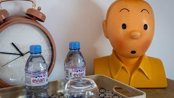 Een houten dienblad met twee Evian waterflessen en een glazen glas.