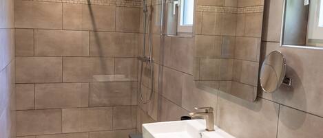 A modern bathroom with a glass-enclosed shower, a built-in sink, and a mirror.